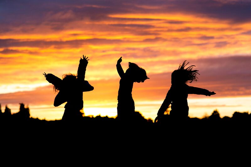 Crianças a saltar em silhueta durante um pôr-do-sol